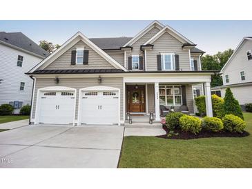Charming two-story home featuring a covered front porch, a two-car garage, and manicured landscaping at 2083 Amalfi Pl, Apex, NC 27502