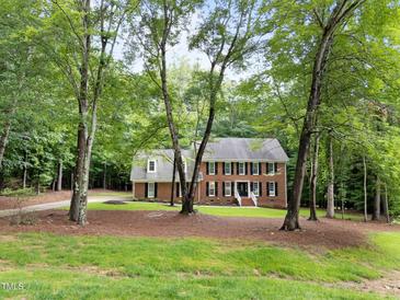 Traditional two-story brick home with a symmetrical facade and a welcoming front porch surrounded by mature trees at 221 Jansmith Ln, Raleigh, NC 27615
