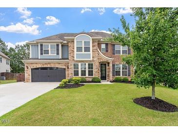 Beautiful two story home with a well manicured lawn, stone and brick exterior, and gray two car garage at 2333 Lantern Walk Ln, Wake Forest, NC 27587