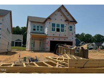 New home construction shows covered in weather proofing with garage and front door, dumpsters, and building materials at 252 Meadowbark Bnd # 46, Garner, NC 27529