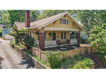 Charming yellow craftsman home with brick accents, a fenced yard, and a welcoming front porch at 311 N Gregson St, Durham, NC 27701