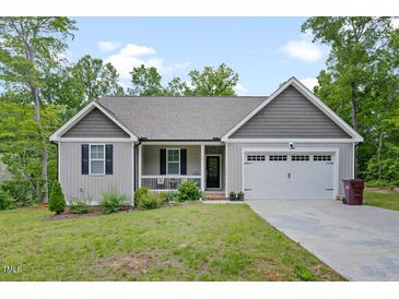 Charming single-Gathering home featuring a well-manicured lawn, attached garage, and inviting front porch at 50 Harriet Gentry Ln, Timberlake, NC 27583