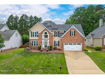 Traditional two-story home featuring a brick and siding exterior, well-manicured lawn, and two-car garage at 8913 Walking Stick Trl, Raleigh, NC 27615
