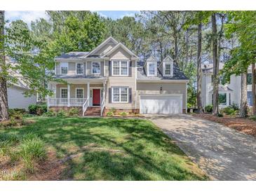 Traditional two-story home with a well-manicured lawn, red door, and white trim at 9308 Carisbrook Ct, Raleigh, NC 27615