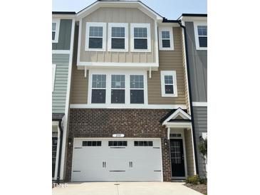Inviting townhome with brick facade, white garage door, and neutral-toned siding at 10011 Secluded Gdn Dr # 169, Apex, NC 27523