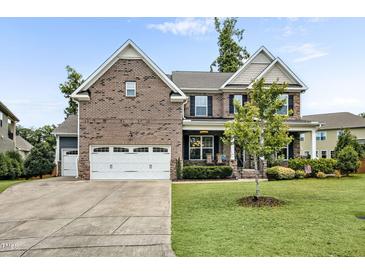 Beautiful two-story brick home with a manicured lawn and three-car garage on a sunny day at 2100 Della Ct, Apex, NC 27502