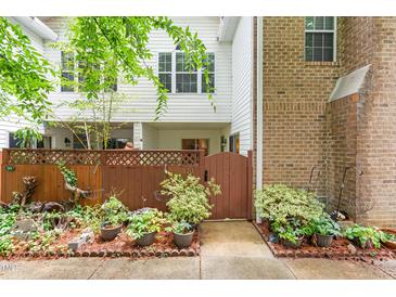 Inviting townhome entrance with a wooden gate, lush landscaping, and a charming courtyard at 320 Summerwalk Cir, Chapel Hill, NC 27517