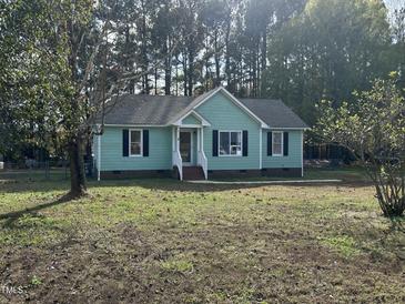 Charming single-story home with a light-green exterior and black shutters, surrounded by a spacious yard at 803 Flat Rock Church Rd, Louisburg, NC 27549