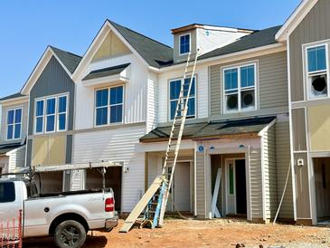 Modern townhomes under construction feature stylish exteriors, windows, and a truck with ladders nearby at 83 Ripple Way # 215, Clayton, NC 27520