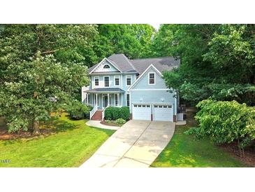 Charming two-story home with a well-manicured lawn, a two-car garage, and lush, mature landscaping at 1128 Neuse Ridge Dr, Clayton, NC 27527