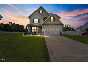 Inviting two-story home featuring a manicured lawn and a charming two-car garage, displayed under a captivating twilight sky at 15 Scuppernong Ln, Lillington, NC 27546