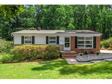Charming single-story home featuring a brick facade, well-manicured lawn, and inviting entrance, surrounded by lush greenery at 202 Crest Rd, Cary, NC 27513