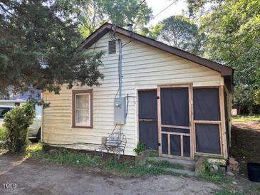 Cozy home featuring a small, enclosed porch entrance and weathered wood siding with a chair outside at 207 2Nd St, Erwin, NC 28339