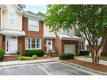 Charming townhome featuring brick facade, one car garage, and meticulously manicured landscaping at 222 Ashton Hall Ln, Raleigh, NC 27609