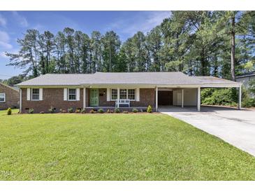 Charming brick home featuring a well-manicured lawn, covered parking, and a vibrant green door at 3009 Wellington Dr, Rocky Mount, NC 27803