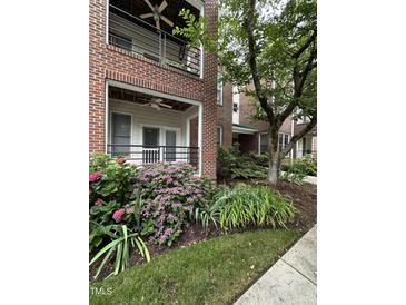 Brick condo exterior features colorful hydrangeas, lawn, sidewalk, porch, and black railing at 710 N Person St # 103, Raleigh, NC 27604