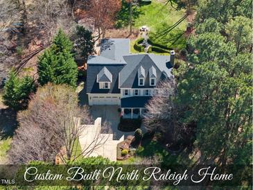Stunning aerial view of the custom-built home featuring a manicured lawn, stone seating area, and mature landscaping at 1006 Henny Pl, Raleigh, NC 27614