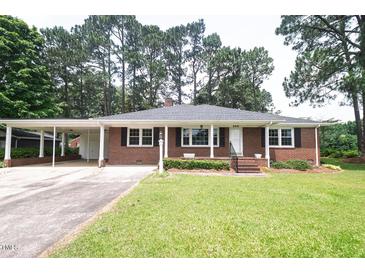 Charming brick home with mature trees and a well-maintained lawn, enhancing curb appeal at 205 N Augusta Ave, Benson, NC 27504