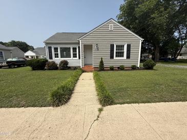 Charming one-story home features a landscaped front yard, sidewalk, and gray siding at 306 W Canary St, Dunn, NC 28334