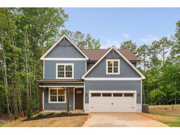 Charming two-story home featuring a blue exterior, a two-car garage and a well manicured front yard at 125 Oswego Dr, Louisburg, NC 27549