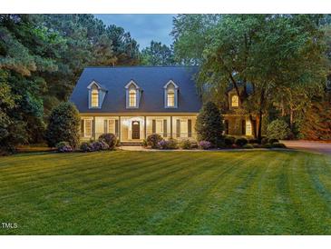 Charming two-story home with a lush green lawn, manicured landscaping, and mature trees at dusk at 5344 Mill Dam Rd, Wake Forest, NC 27587