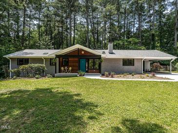Charming brick home with a well-manicured lawn and a welcoming teal front door at 5809 Kimbal St, Raleigh, NC 27606