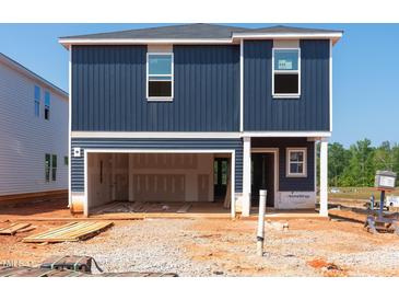 Two story home exterior with blue siding, garage, and construction materials surrounding the property at 800 Ottawa Dr, Garner, NC 27529