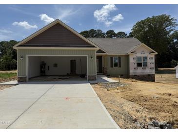 Charming single-story home with attached garage and well-lit entranceway on a sunny day at 145 Tee Dr, Selma, NC 27576