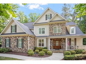 Charming stone and siding home featuring manicured landscaping and a welcoming front porch at 286 Harrison Pond Dr, Pittsboro, NC 27312