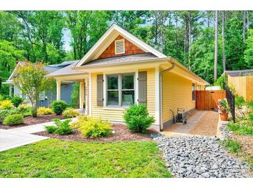 Charming yellow cottage-style home with well-manicured landscaping, stone pathway, and inviting curb appeal at 2975 Carolyn Dr, Durham, NC 27703
