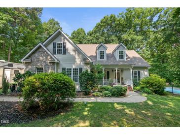Charming two-story home featuring a stone facade, inviting front porch, and lush landscaping at 395 Timberlands Dr, Louisburg, NC 27549