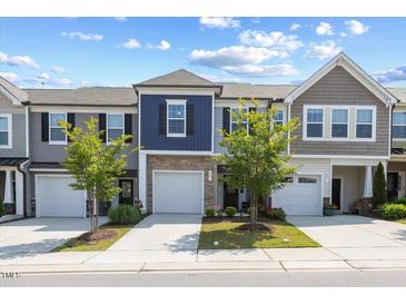 Attractive townhomes with garages and manicured lawns under a partly cloudy sky at 44 Bordeaux Dr, Clayton, NC 27527