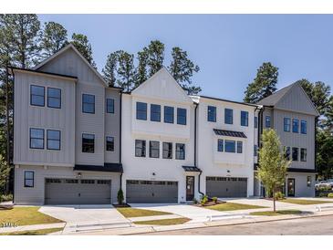 Modern townhomes feature varied exteriors, private garages, and manicured lawns against a blue sky at 4502 Mint Leaf Ln, Raleigh, NC 27612