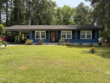 Charming blue single-story home featuring a lush front yard and covered carport at 509 Forest Ridge Rd, Garner, NC 27529