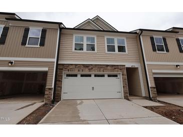 New two-story townhouse with neutral siding, stone accents, attached two-car garage and driveway at 6973 Doddridge Ln # 17, Cary, NC 27519
