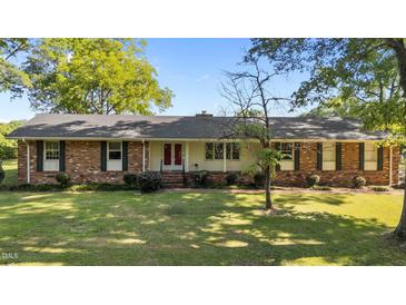 Charming single-story brick home featuring a lush front yard and a welcoming red double-door entrance at 129 Castle Dr, Smithfield, NC 27577