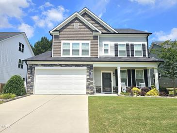 Charming two-story home featuring a well-manicured lawn and a stone-accented facade with a two-car garage at 1412 Queen Trigger Dr, Fuquay Varina, NC 27526