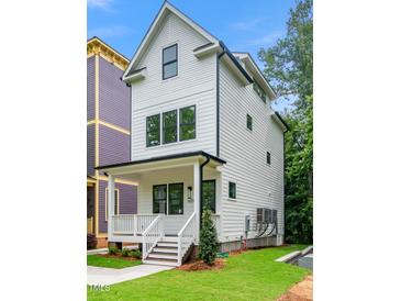 Charming two-story home with a welcoming front porch, black trim windows and a well-manicured lawn at 1621 Ella Wiggins Way, Raleigh, NC 27603