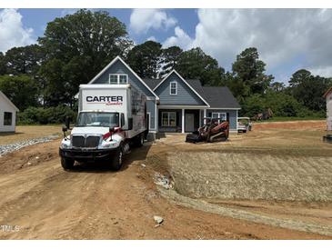 New construction home with blue siding, landscaping, and a Carter Lumber truck in the driveway at 183 Tee Dr, Selma, NC 27576
