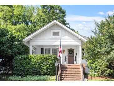 Charming white cottage with brick steps, lush landscaping, and an American flag at 2225 Creston Rd, Raleigh, NC 27608