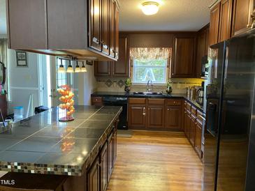 Well-lit kitchen features wood cabinets, black appliances, and a large island with seating at 3298 Oakridge Dr # A, Graham, NC 27253