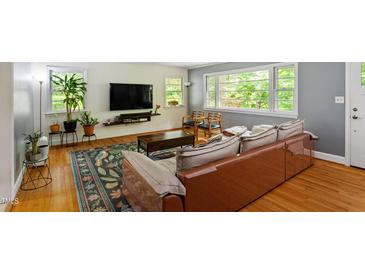 Inviting living room with hardwood floors, a large window, comfortable seating and colorful area rug at 7 Woodward Way, Chapel Hill, NC 27516