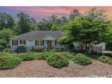 Charming single-story home with black shutters, wrought iron fence and lush landscaping at 877 Millcroft, Pittsboro, NC 27312