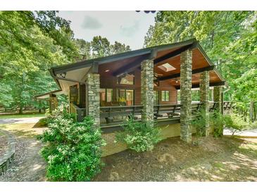 Stunning exterior elevation of a cabin-style home featuring stone pillars and a cozy porch area surrounded by lush trees at 110 Wolfs Trl, Chapel Hill, NC 27516