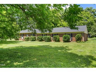 Charming brick home features a well-manicured lawn and mature trees, offering a serene and inviting curb appeal at 250 Dixon Rd, Graham, NC 27253