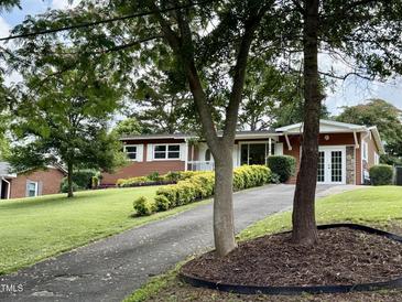 Charming single-story home with well-manicured lawn, featuring vibrant shrubbery and mature trees at 2909 Sprucewood Dr, Durham, NC 27707