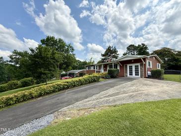 Charming single-story home with siding, double doors, concrete driveway, and lush landscaping at 2909 Sprucewood Dr, Durham, NC 27707
