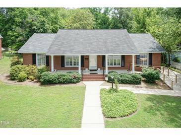 Charming brick home featuring a well-manicured front lawn and an inviting covered porch at 303 Spring St, Louisburg, NC 27549