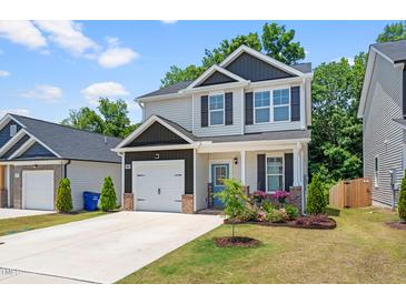 Charming two-story home featuring a bright blue door, attached garage, and a well-manicured lawn with flower beds at 445 Sturgeon St, Smithfield, NC 27577