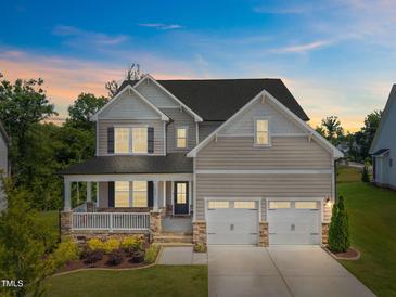 Charming two-story home with a welcoming front porch, stone accents, and a well-manicured lawn under a beautiful sky at 525 Marion Hills Way, Knightdale, NC 27545